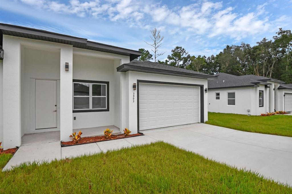 A modern single-story house with a white exterior, a two-car garage, and a front porch — 205 AUSTRALIAN DRIVE, ROTONDA WEST, FL