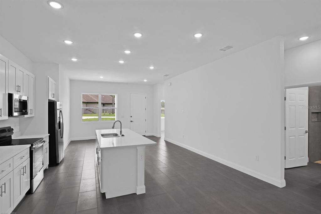 A modern kitchen features white cabinetry, a central island, and dark tile flooring — 205 AUSTRALIAN DRIVE, ROTONDA WEST, FL