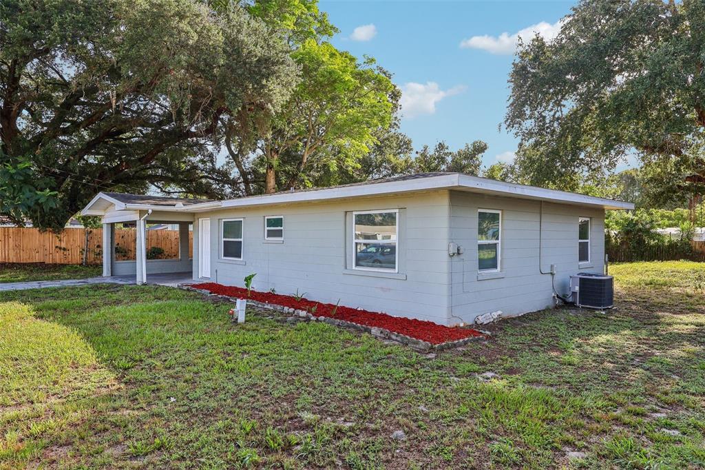 A single-story gray house with a carport sits on a grassy lot with trees — 1680 32ND STREET NW, WINTER HAVEN, FL
