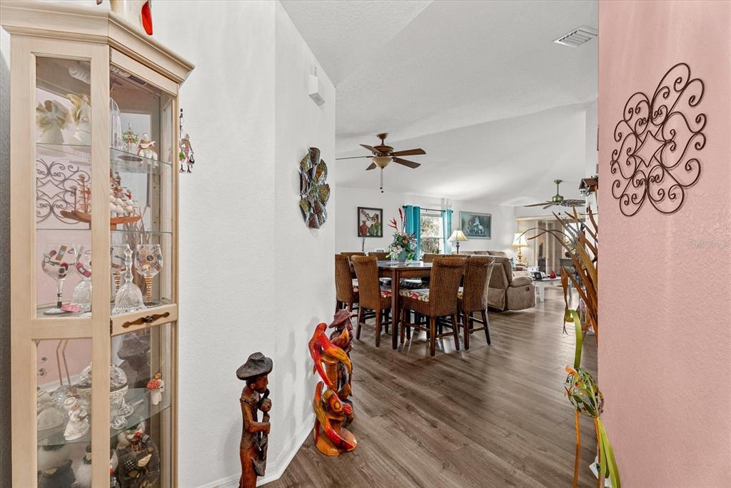 A view from a hallway into a dining room and living area with wood flooring — 5800 SABAL TRACE DRIVE UNIT 1204, NORTH PORT, FL