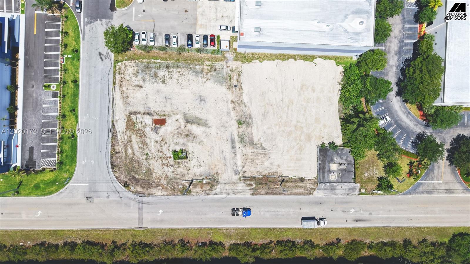 An aerial view shows a vacant, cleared rectangular lot situated between paved parking areas — 11501 NW 124th St, Medley FL 33178, MEDLEY, FL