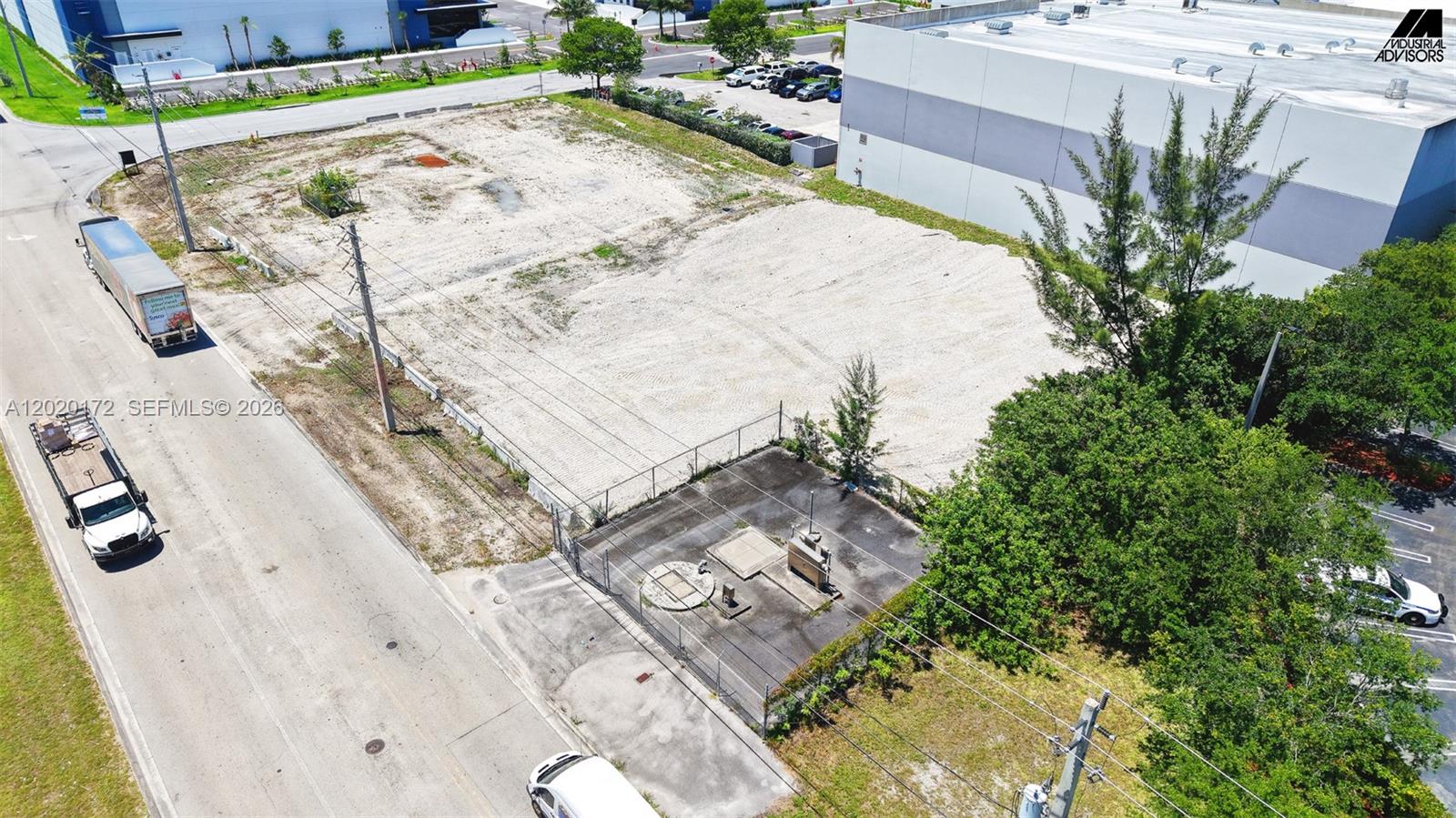 An aerial view shows a vacant, fenced dirt lot next to a large industrial building — 11501 NW 124th St, Medley FL 33178, MEDLEY, FL