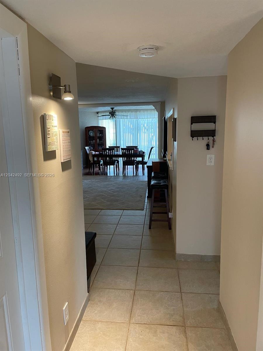A tiled hallway leads to a dining area with a table and chairs — 9520 Seagrape Dr # 106, Davie FL 33324, DAVIE, FL