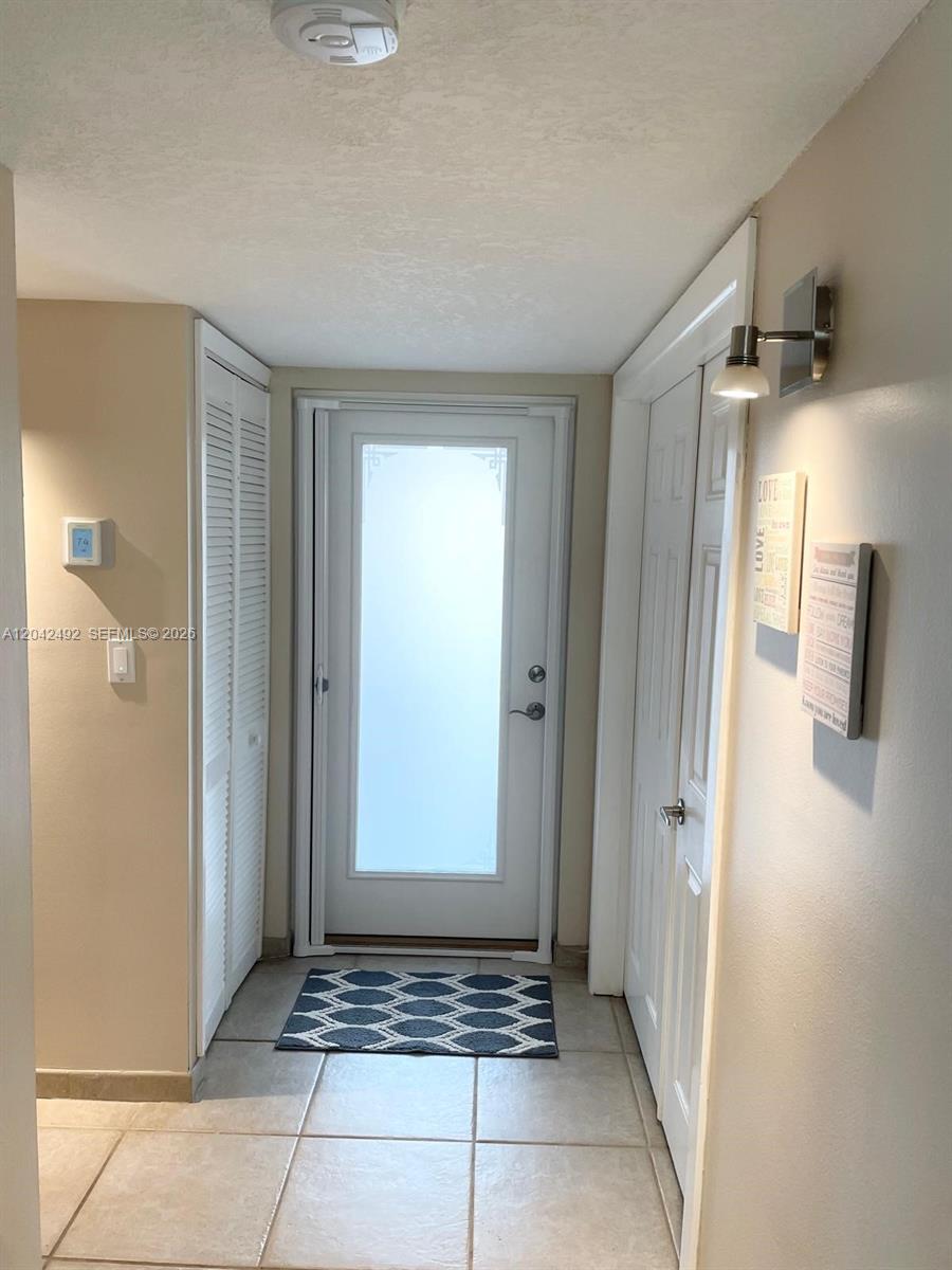 A tiled entryway features a white front door, louvered closet doors, and wall-mounted decor — 9520 Seagrape Dr # 106, Davie FL 33324, DAVIE, FL