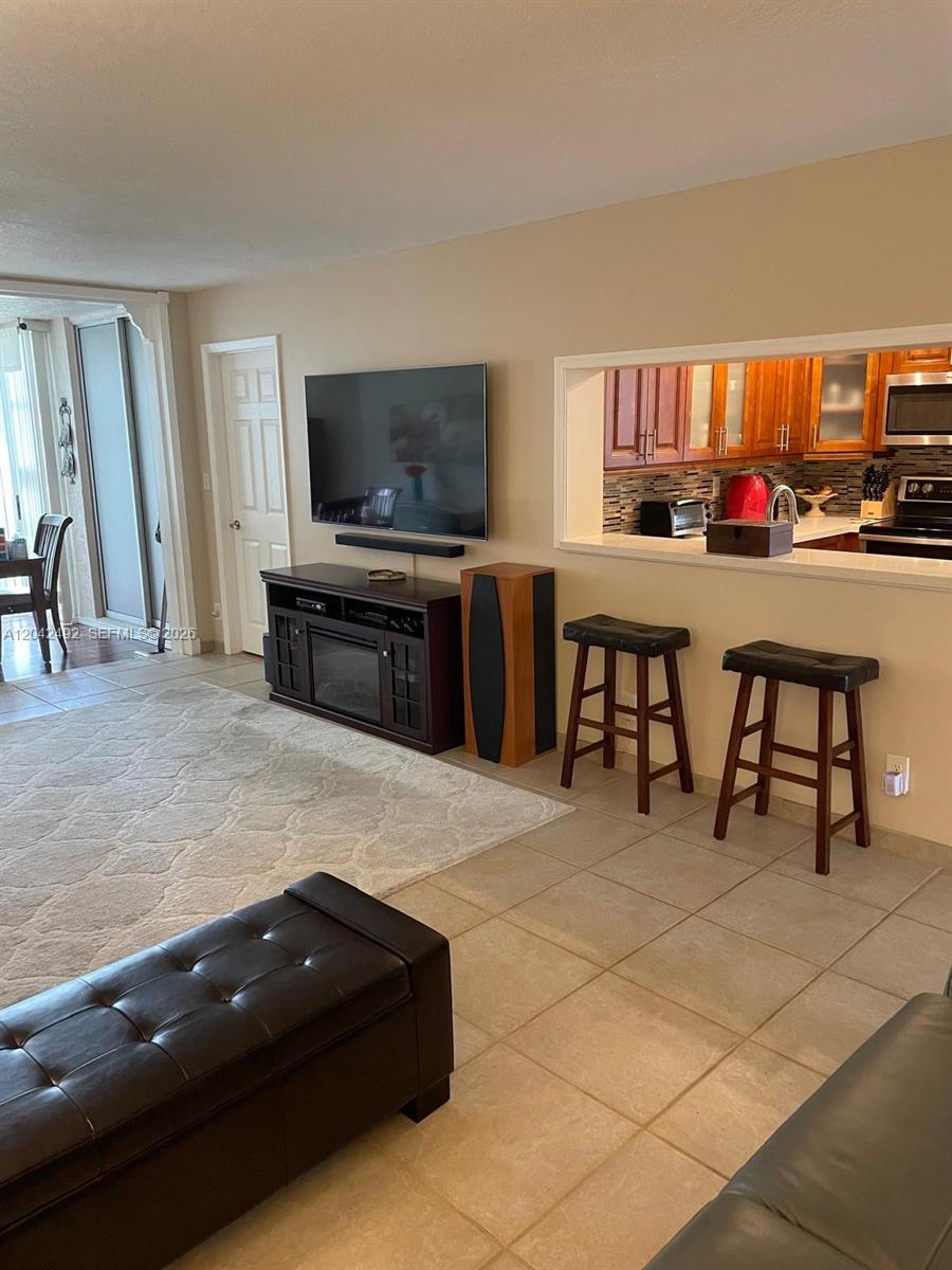 A living room with a television, fireplace console, and a breakfast bar with stools — 9520 Seagrape Dr # 106, Davie FL 33324, DAVIE, FL