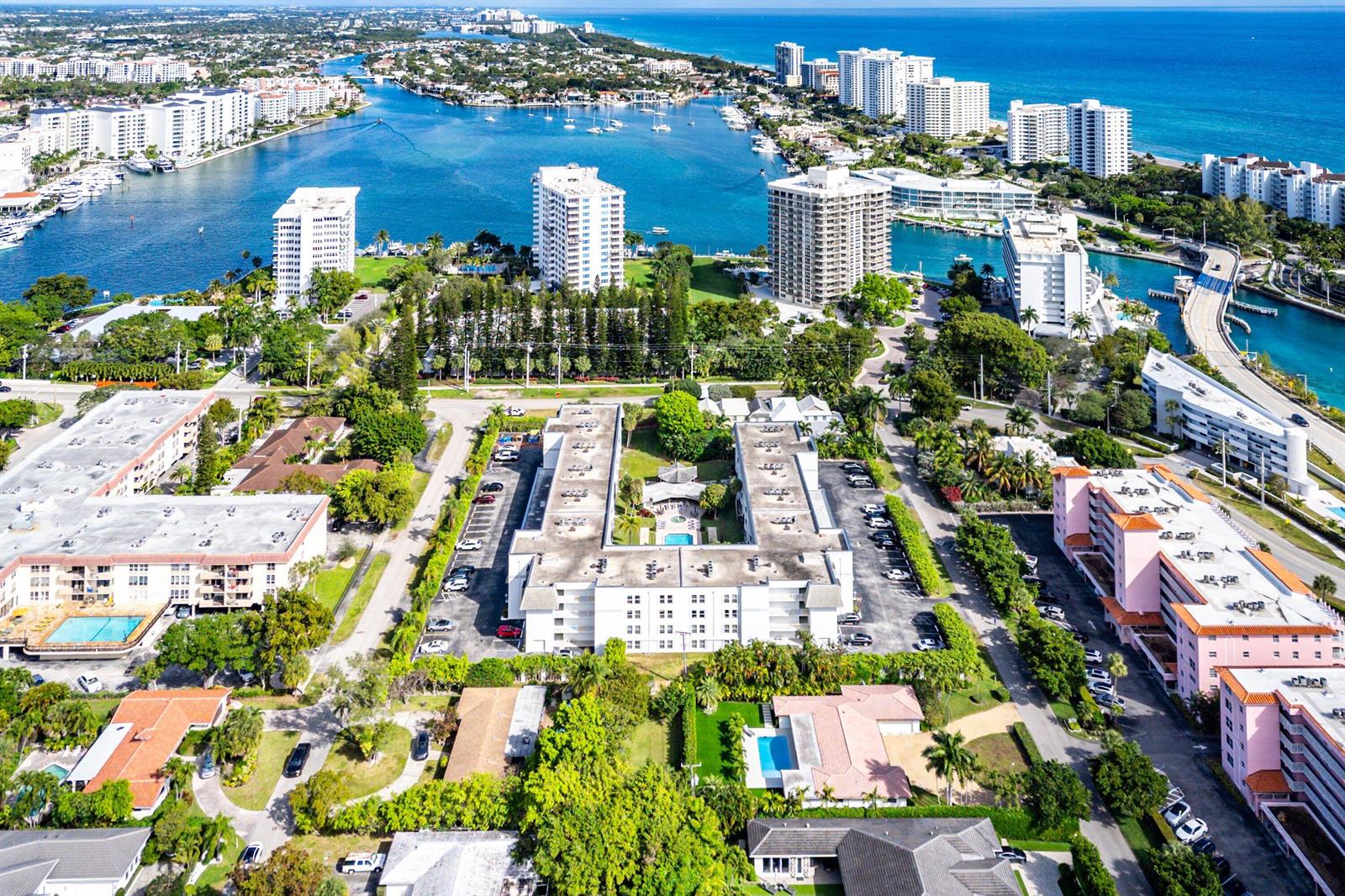 Aerial view of a residential complex with a central courtyard pool near a coastal waterway — 800 E Camino Real # 409, Boca Raton FL 33432, BOCA RATON, FL