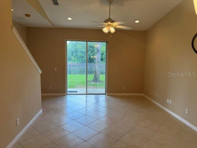 An empty room with beige walls, tile flooring, a ceiling fan, and sliding glass doors — 472 HARBOR WINDS COURT, WINTER SPRINGS, FL