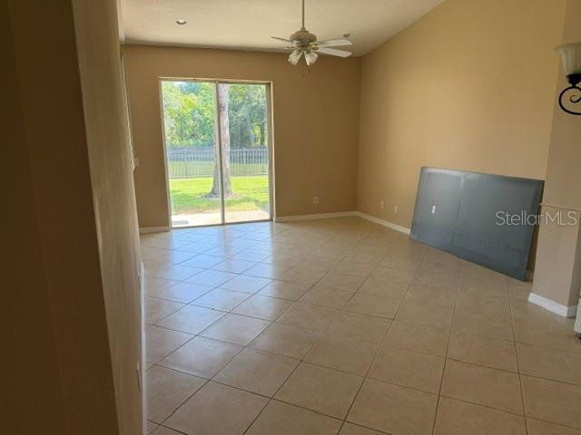 A living room with beige tile floors, a ceiling fan, and sliding glass doors — 472 HARBOR WINDS COURT, WINTER SPRINGS, FL
