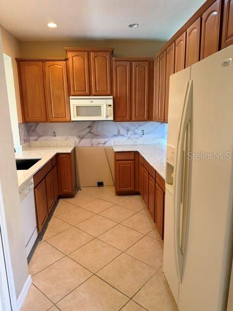 A kitchen with wood cabinets, light countertops, a white microwave, and tiled flooring — 472 HARBOR WINDS COURT, WINTER SPRINGS, FL