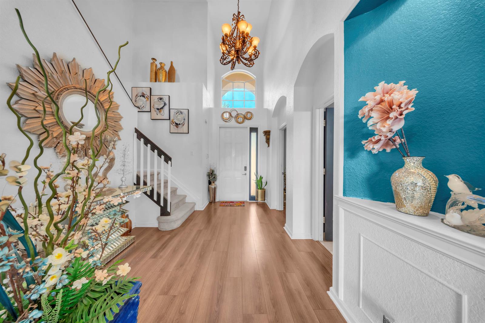 A bright foyer features wood-look flooring, a high ceiling with a chandelier, and a staircase — 726 Gazetta Way, West Palm Beach FL 33413, WEST PALM BEACH, FL