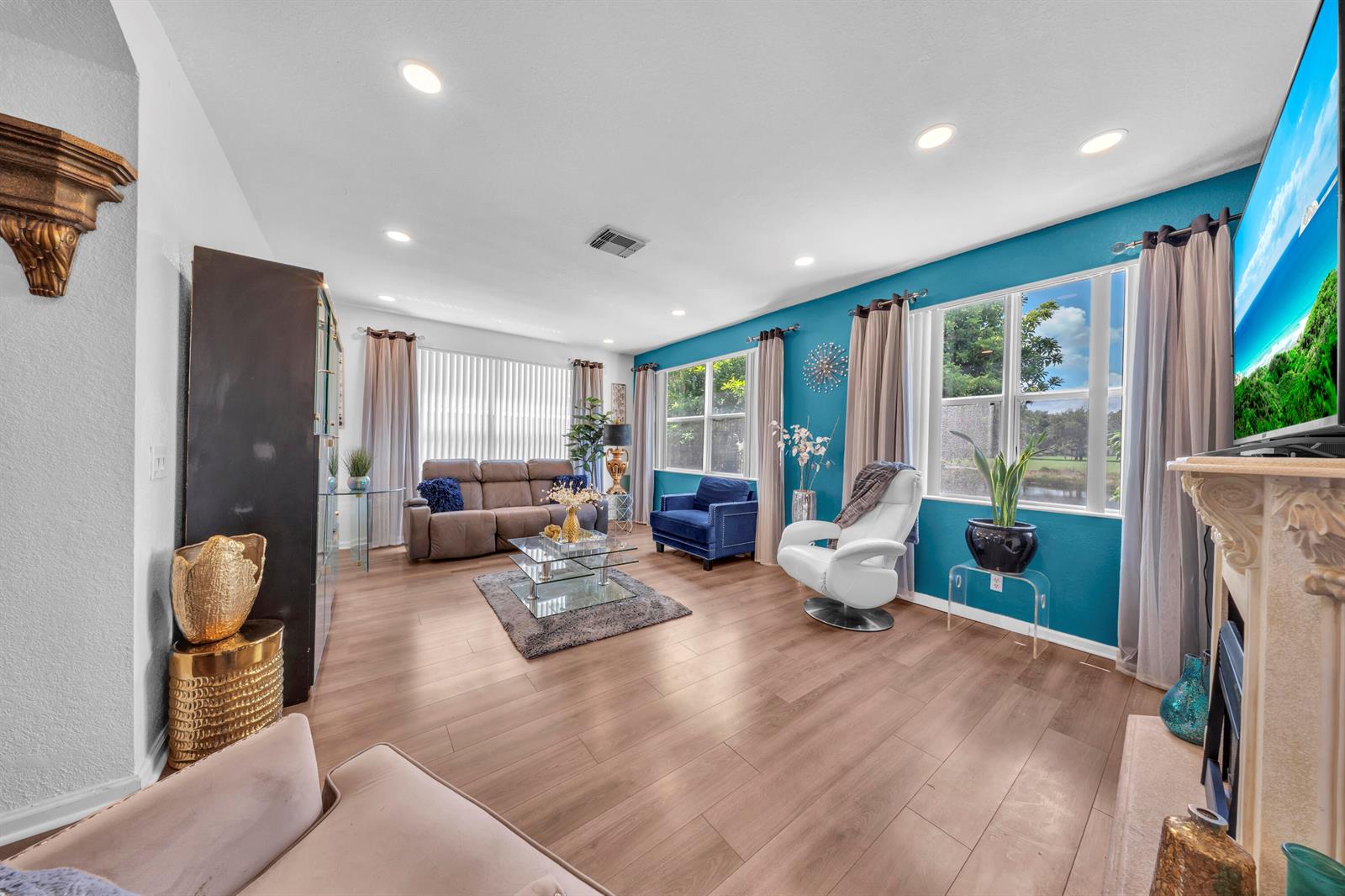 A living room features wood-look flooring, a teal accent wall, and a large television — 726 Gazetta Way, West Palm Beach FL 33413, WEST PALM BEACH, FL