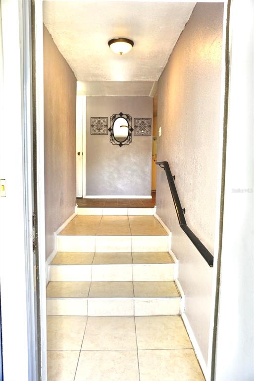 A tiled staircase leads up to a hallway featuring a wall mirror and decorative art — 980 7TH STREET NW UNIT 71, LARGO, FL