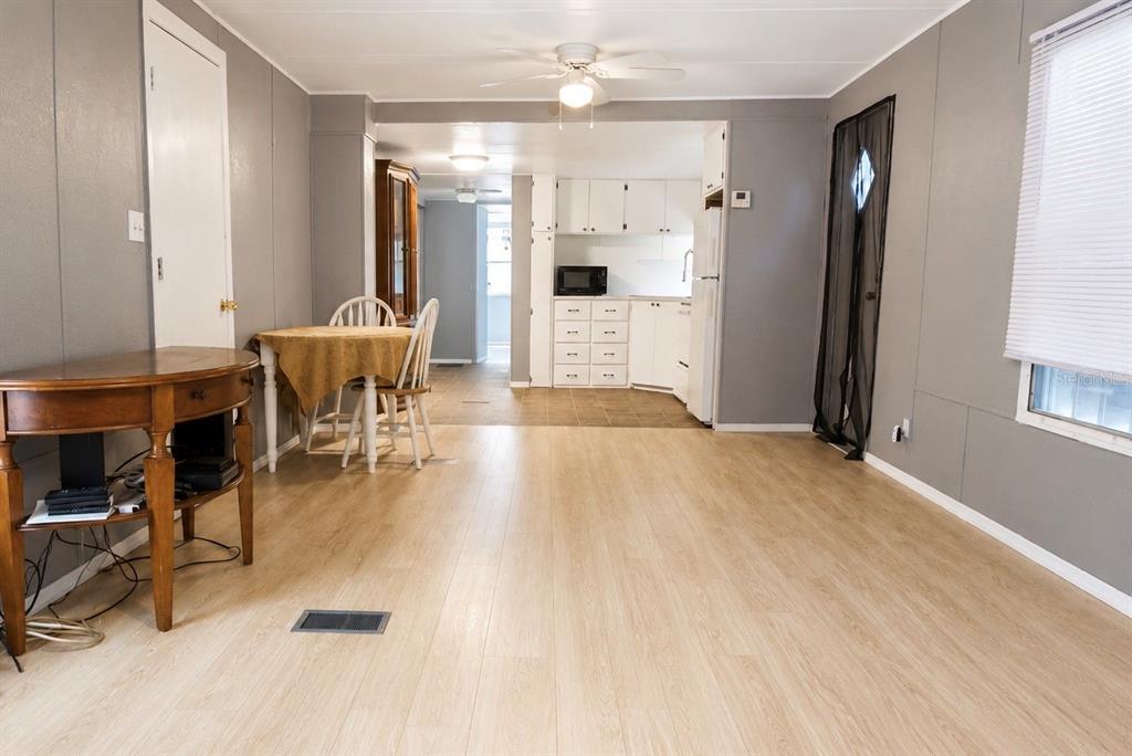 A living room with light wood flooring leads into a kitchen with white cabinets — 980 7TH STREET NW UNIT 71, LARGO, FL