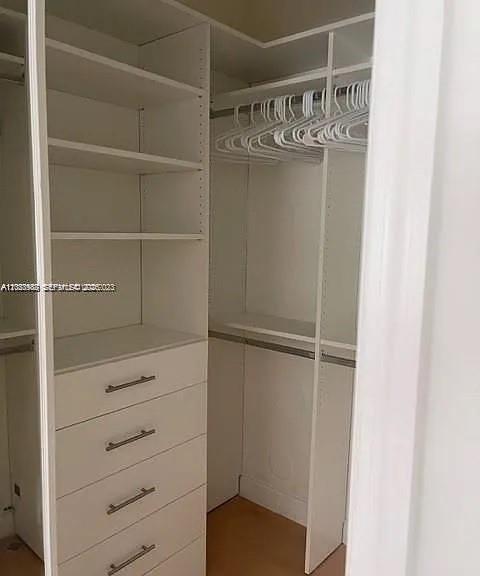 A walk-in closet features white shelving, a four-drawer dresser, and hanging rods with plastic hangers — 7778 NW 116th Ave # 0, Doral FL 33178, DORAL, FL