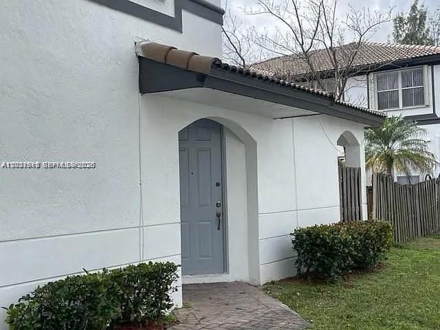 A white stucco house exterior features a gray front door under a small tiled awning — 7778 NW 116th Ave # 0, Doral FL 33178, DORAL, FL
