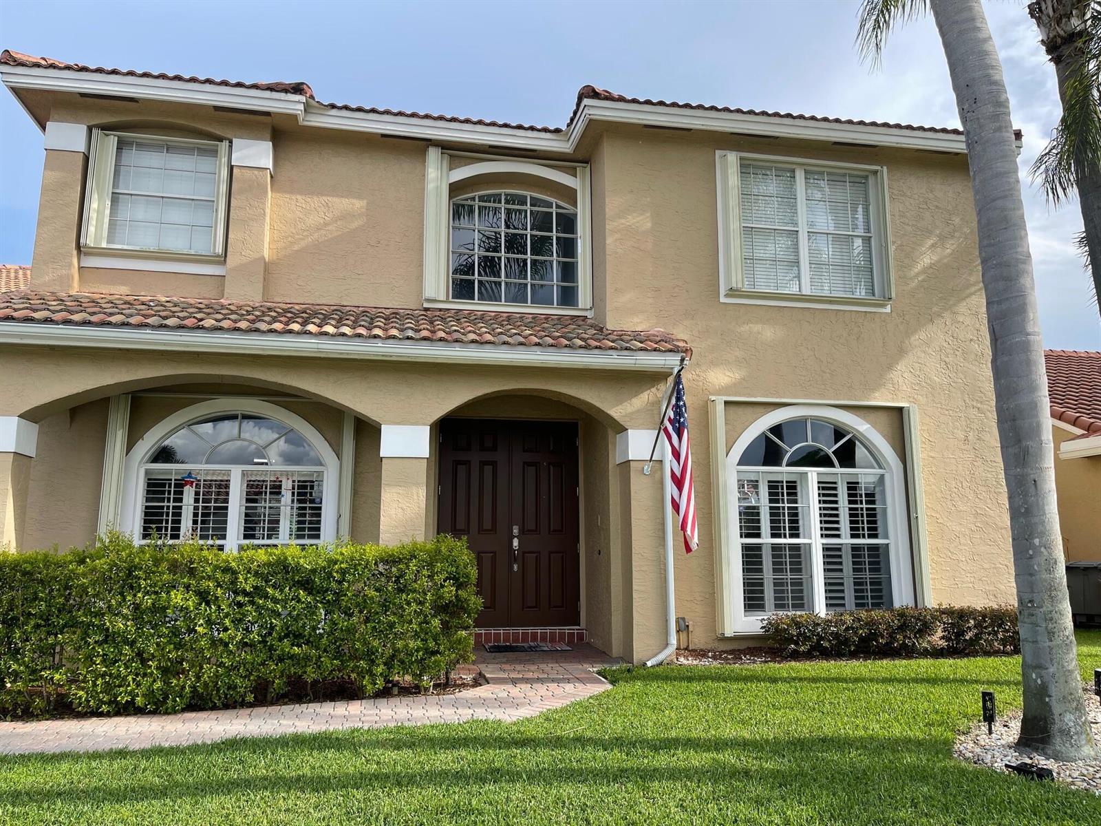 A two-story tan stucco house with a tile roof, arched windows, and a front entrance — 9460 Lake Serena Drive, Boca Raton FL 33496, BOCA RATON, FL
