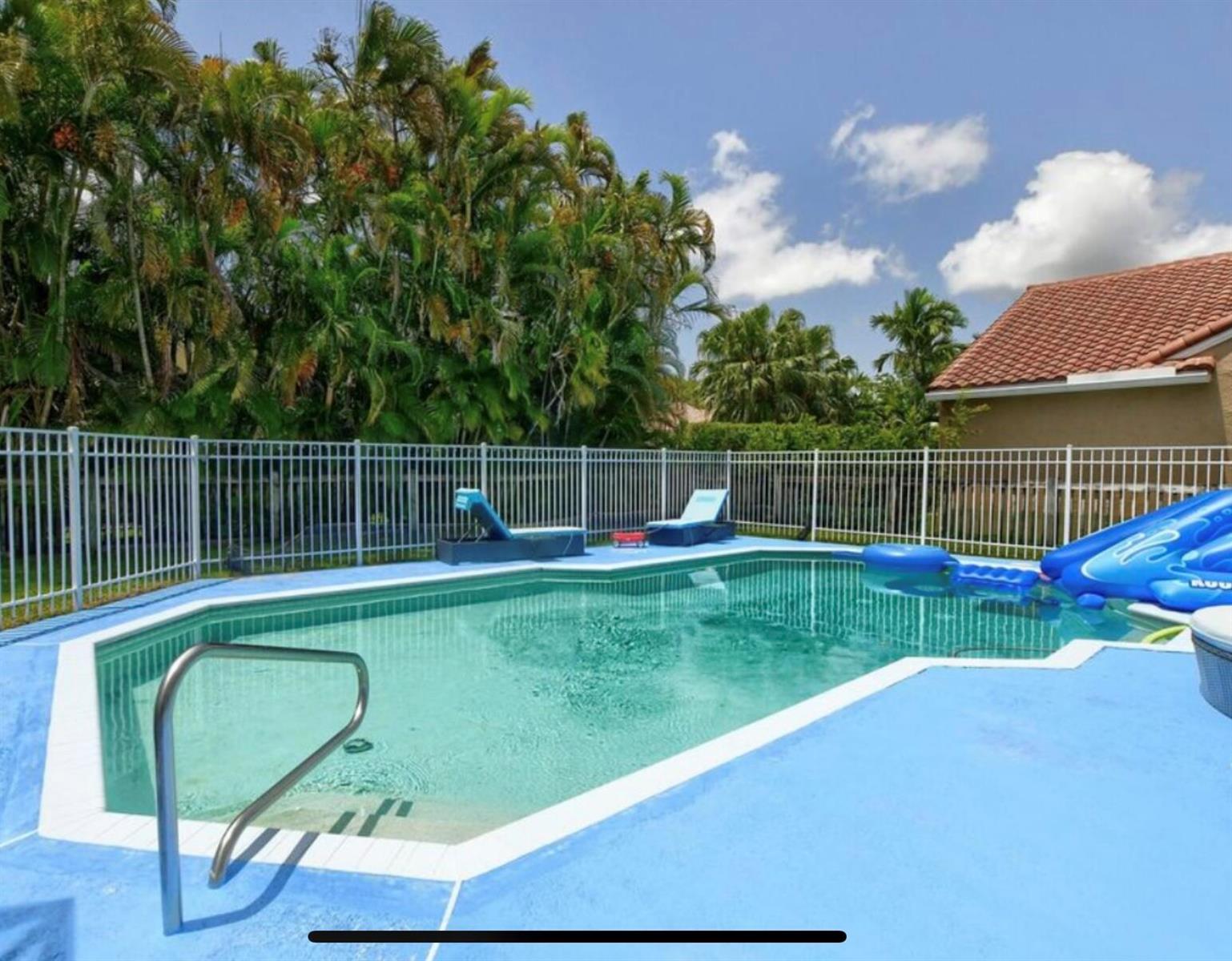A backyard swimming pool with a blue slide, lounge chairs, and a white metal fence — 9460 Lake Serena Drive, Boca Raton FL 33496, BOCA RATON, FL
