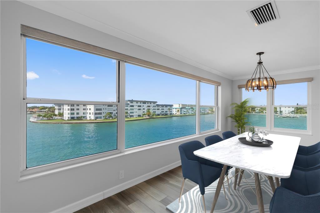 A dining room with a marble table, blue chairs, and large windows overlooking the water — 6075 SHORE BOULEVARD S UNIT 315, GULFPORT, FL
