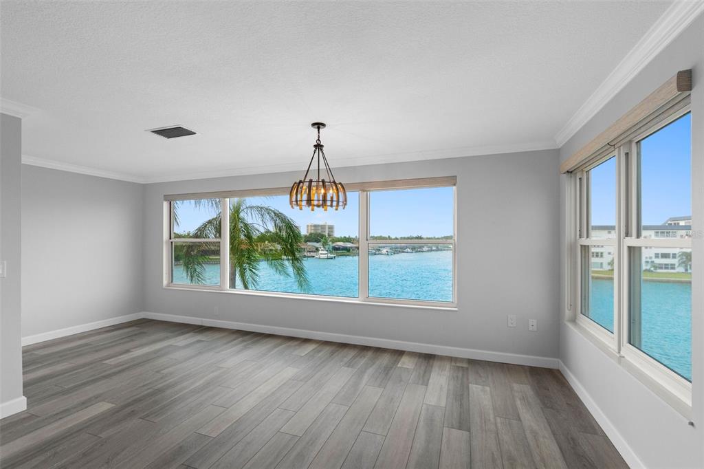 An empty room with gray wood-look flooring and large windows overlooking a waterfront view — 6075 SHORE BOULEVARD S UNIT 315, GULFPORT, FL