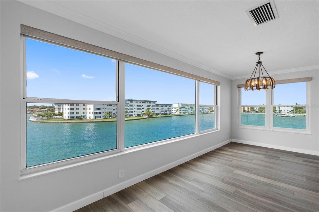An empty room with wood-look flooring and large windows overlooking a bay and buildings — 6075 SHORE BOULEVARD S UNIT 315, GULFPORT, FL