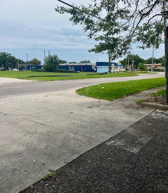 An outdoor view of a paved driveway leading toward a street and a blue building — 101 W MAIN STREET, APOPKA, FL
