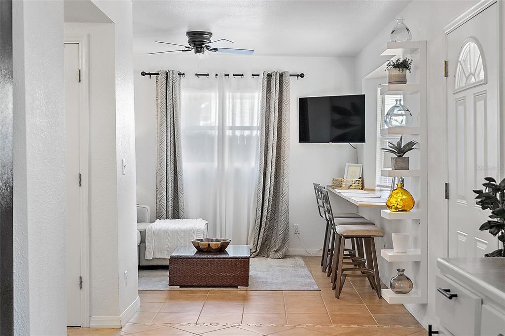 A living area features tile flooring, a window with curtains, a wall-mounted TV, and shelving — 2810 2ND AVENUE S UNIT B, ST PETERSBURG, FL