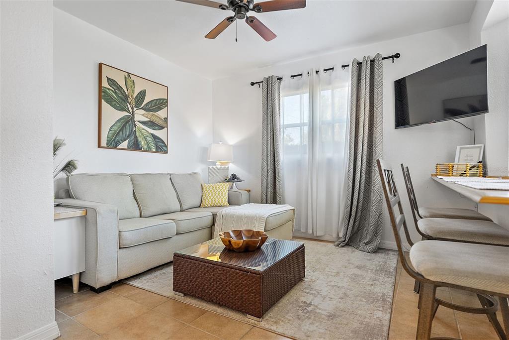 A living room features a light-colored sofa, a wicker coffee table, and a wall-mounted television — 2810 2ND AVENUE S UNIT B, ST PETERSBURG, FL