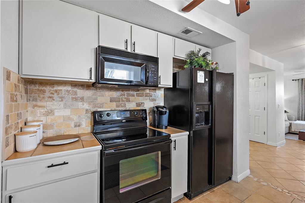 A kitchen features white cabinets, black appliances, a tiled backsplash, and light-colored floor tiles — 2810 2ND AVENUE S UNIT B, ST PETERSBURG, FL