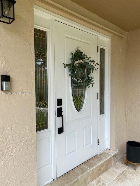 A white front door with a glass insert and wreath is set in a stucco wall — 9760 SW 128th St, Miami FL 33176, MIAMI, FL