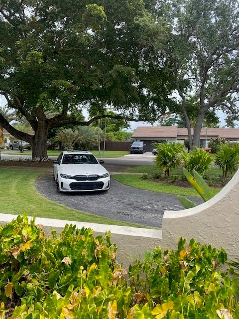 A white sedan is parked on a driveway in front of a house with trees — 9760 SW 128th St, Miami FL 33176, MIAMI, FL