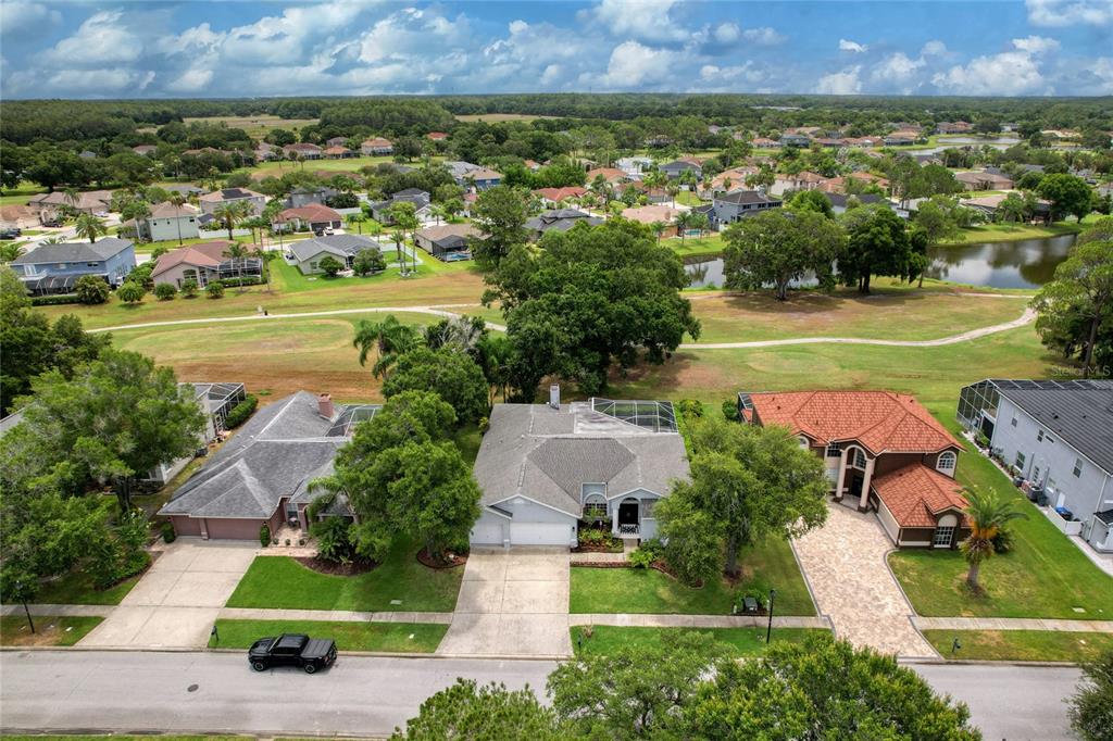 An aerial view shows three suburban houses with driveways and lawns facing a golf course — 16215 HOYLAKE DRIVE, ODESSA, FL