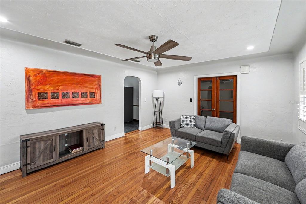 A living room features hardwood floors, a gray sofa, a glass coffee table, and art — 6242 5TH AVENUE N, ST PETERSBURG, FL