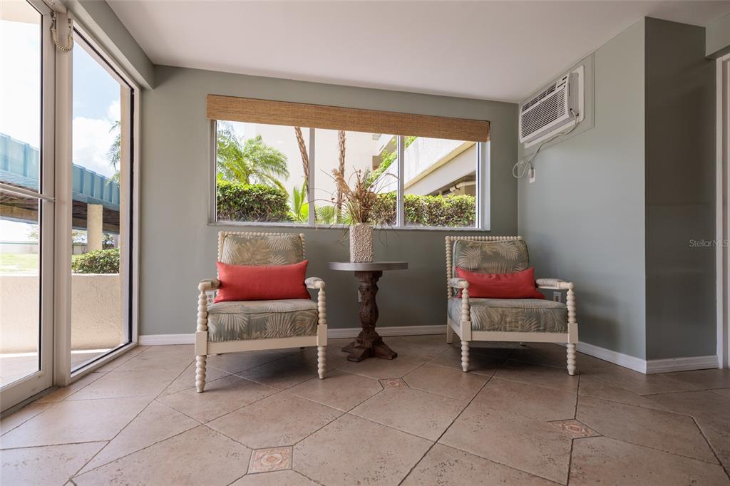 A sunroom features two patterned armchairs with orange pillows, a small table, and tile flooring — 7862 SAILBOAT KEY BOULEVARD S UNIT 506, SOUTH PASADENA, FL