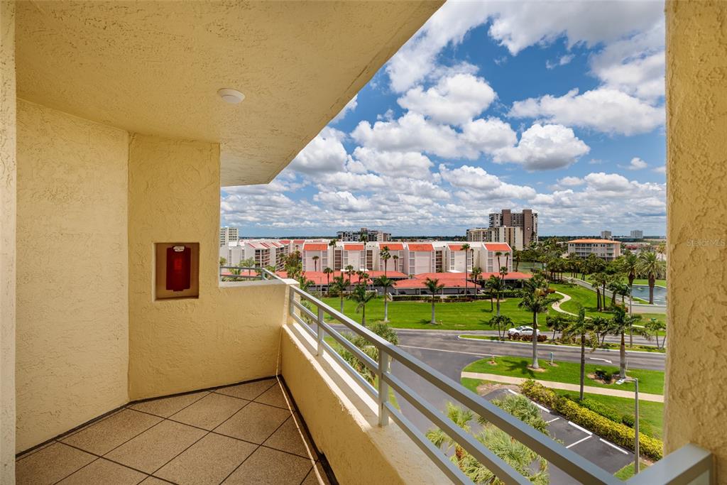A balcony with tiled flooring and metal railings overlooks a green lawn and apartment buildings — 7862 SAILBOAT KEY BOULEVARD S UNIT 506, SOUTH PASADENA, FL