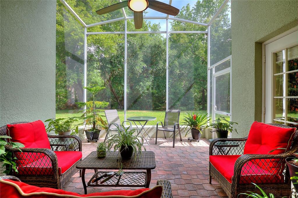 A screened-in patio features red cushioned wicker furniture, a small table, and a ceiling fan — 612 VISTA OAKS WAY, DAVENPORT, FL