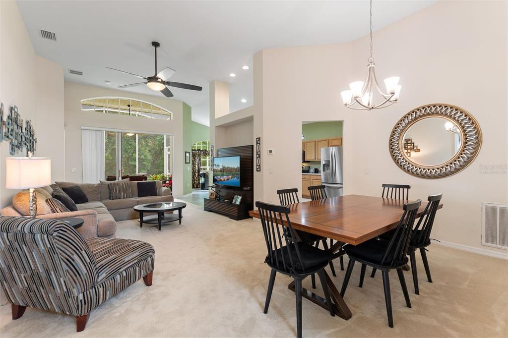 An open-concept living and dining area features a sectional sofa, television, and wooden dining table — 612 VISTA OAKS WAY, DAVENPORT, FL