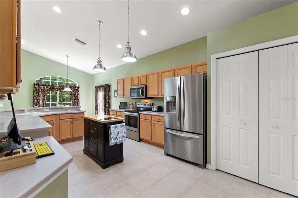 A kitchen features light wood cabinets, a black island, stainless steel appliances, and green walls — 612 VISTA OAKS WAY, DAVENPORT, FL