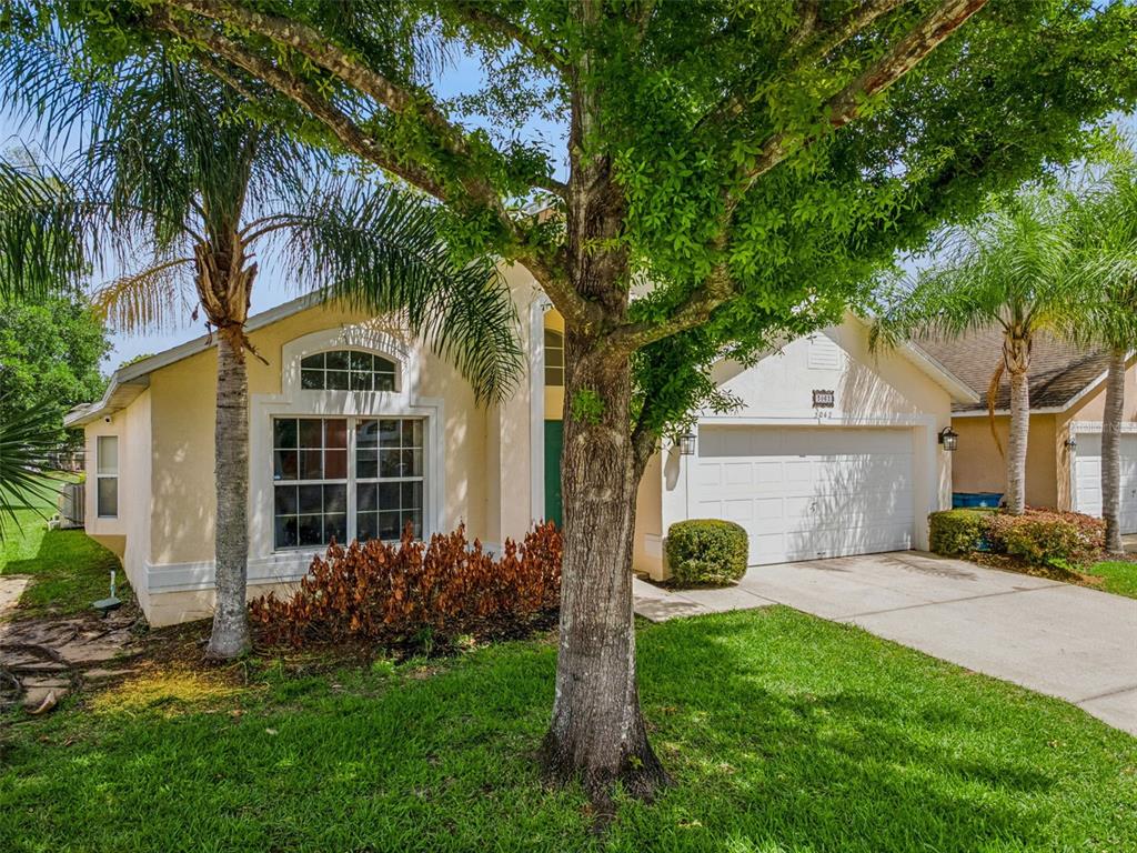 A single-story house with a beige exterior, a two-car garage, and a large front tree — 3062 BARBADOS LANE, HAINES CITY, FL