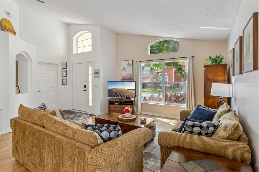 A living room features a tan sofa, a wooden coffee table, and a large window — 3062 BARBADOS LANE, HAINES CITY, FL