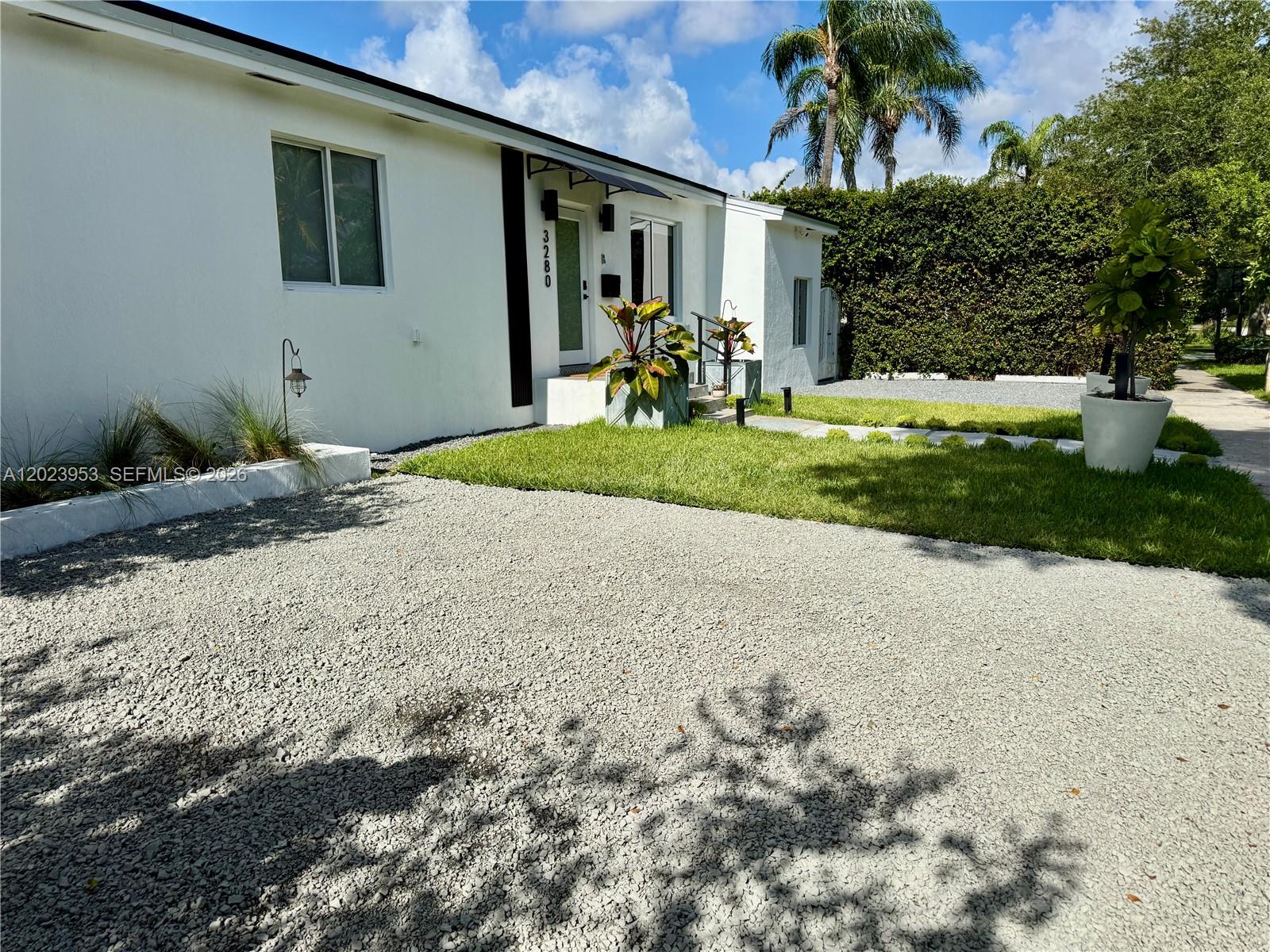 A white house with a gravel driveway, a small lawn, and potted plants in front — 3280 SW 16th Ter, Miami FL 33145, MIAMI, FL