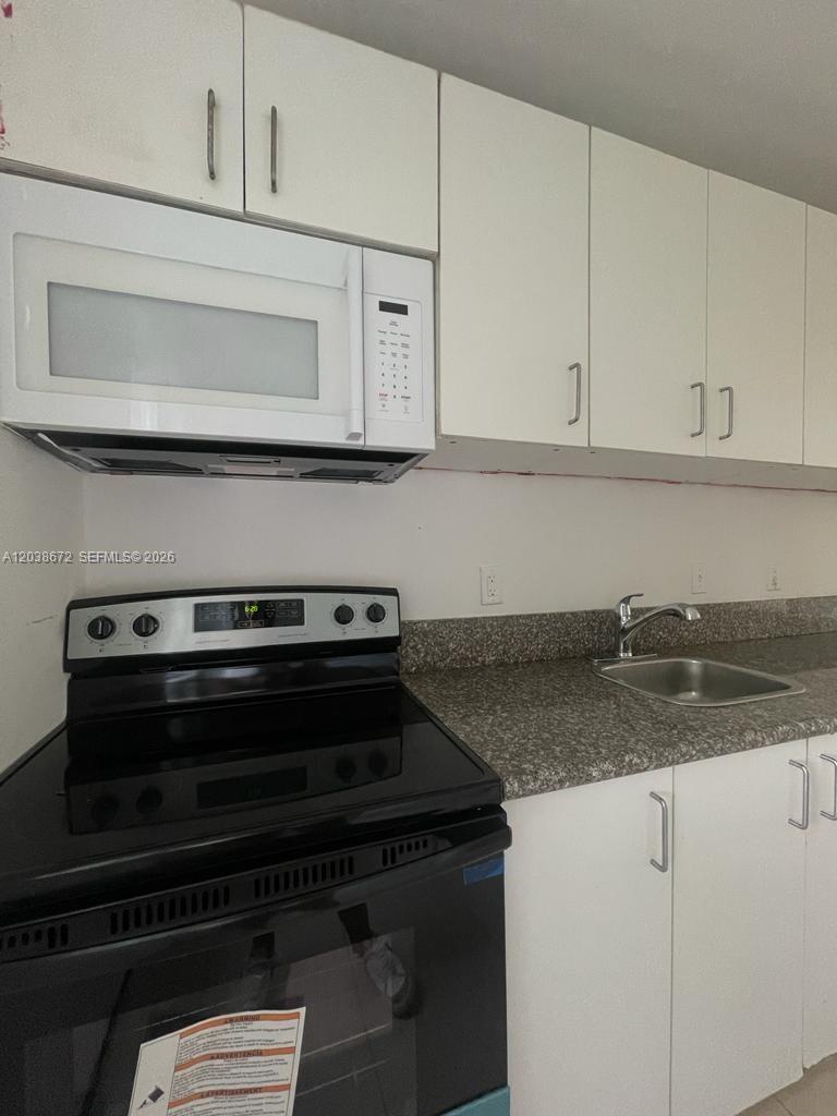 A kitchen features white cabinets, a black electric stove, a microwave, and a granite countertop — 4729 NW 15th Ave # 4727, Miami FL 33142, MIAMI, FL