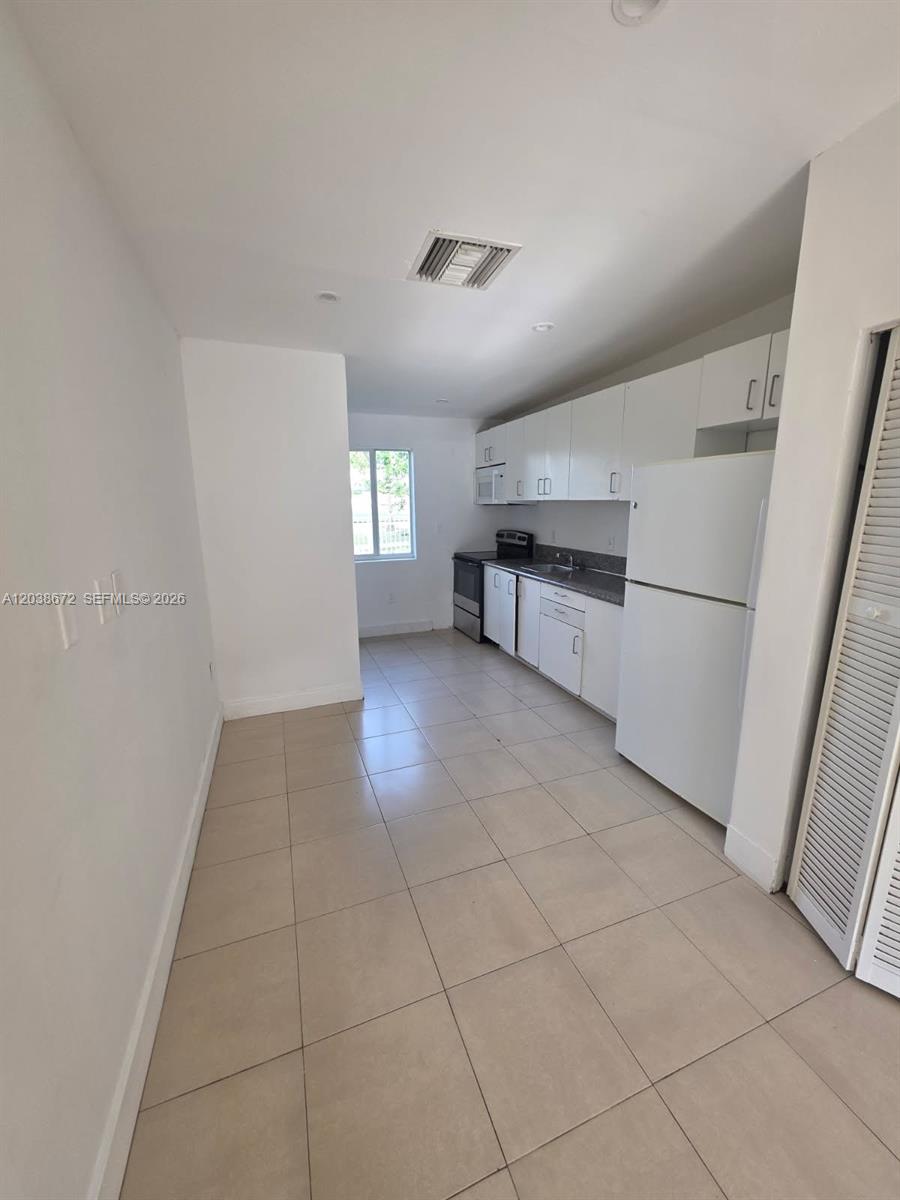 A kitchen features white cabinets, white appliances, and light-colored tile flooring — 4729 NW 15th Ave # 4727, Miami FL 33142, MIAMI, FL