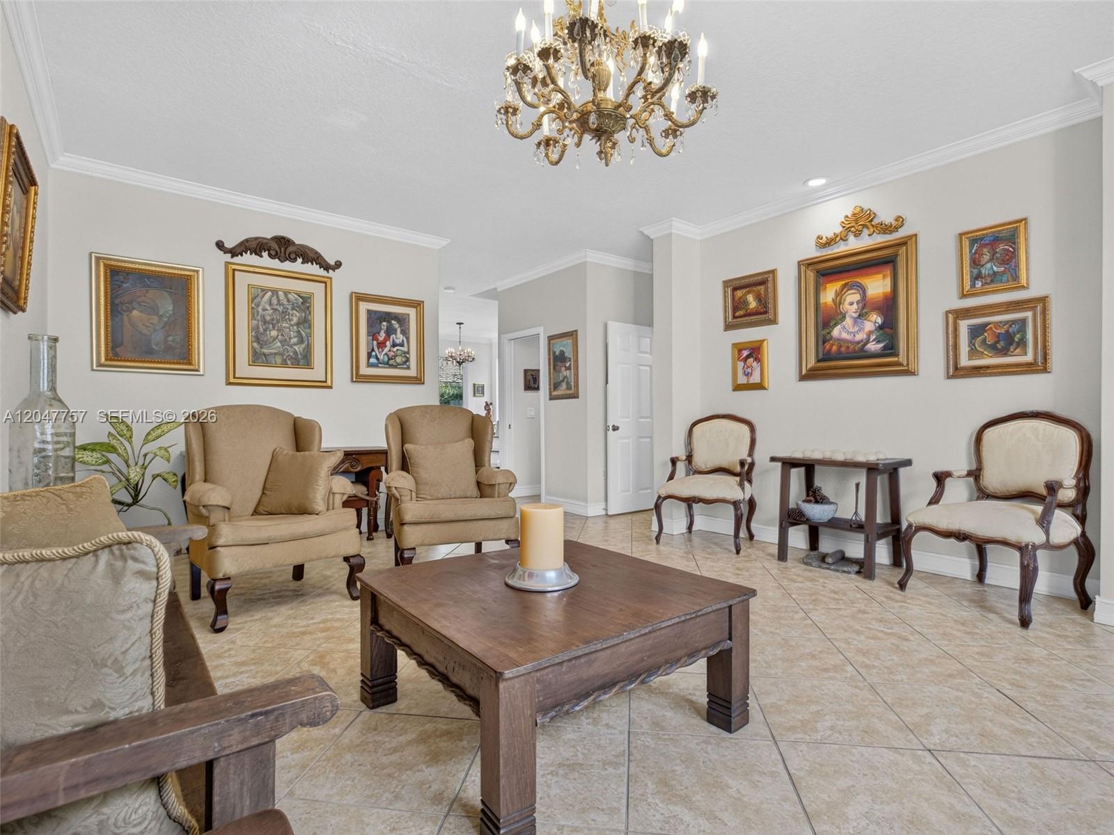 A living room features tile flooring, a chandelier, multiple framed paintings, and various seating arrangements — 18843 SW 26th St, Miramar FL 33029, MIRAMAR, FL