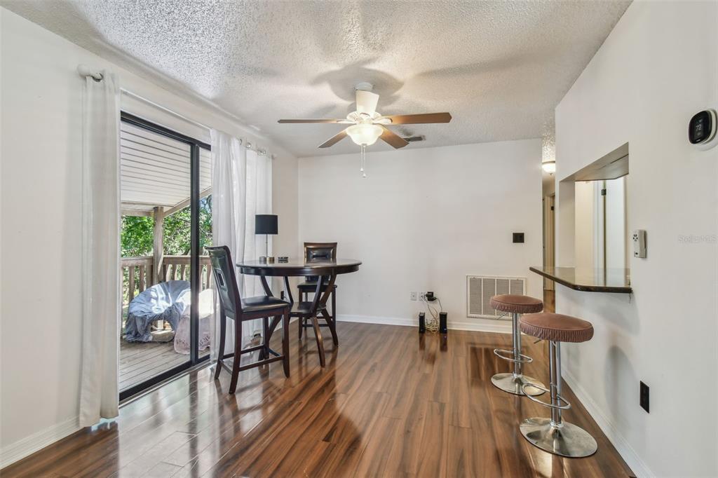 A dining area with wood-look flooring, a ceiling fan, and a sliding door to a deck — 134 SYCAMORE LANE UNIT H, OLDSMAR, FL