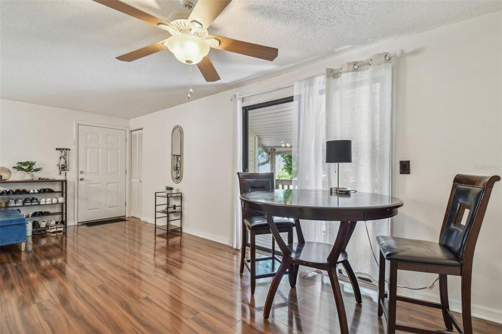 A dining area with wood-look flooring, a round table, and a sliding glass door — 134 SYCAMORE LANE UNIT H, OLDSMAR, FL