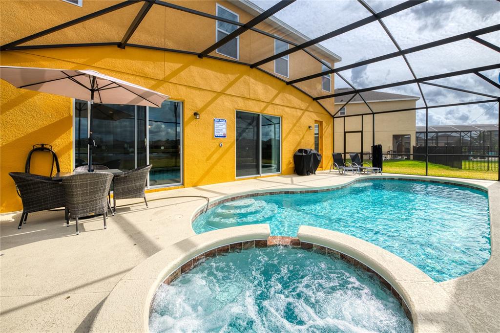 A screened-in patio features a swimming pool, a hot tub, and outdoor dining furniture — 2219 CROFTON SPRINGS COURT, DAVENPORT, FL