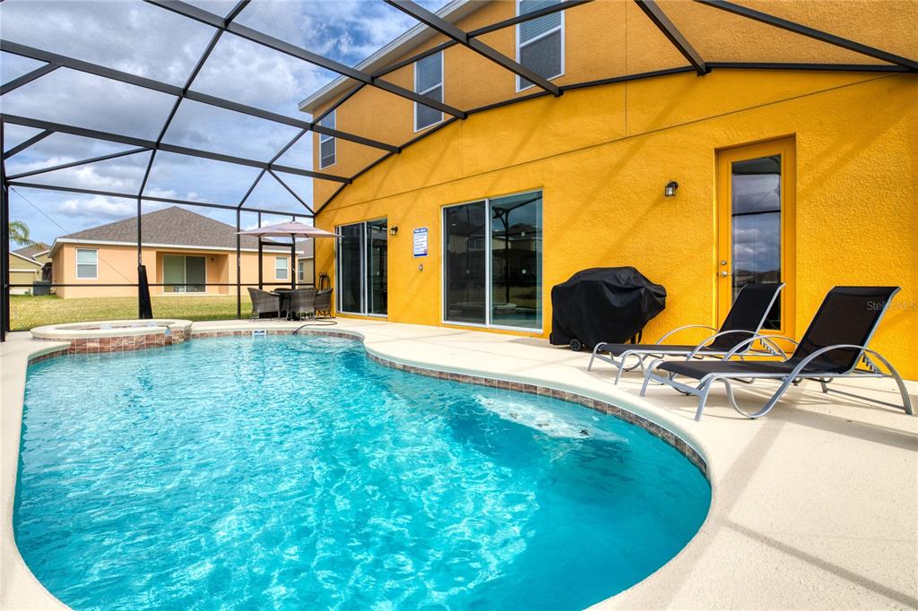 A bright yellow house exterior features a screened-in pool, patio furniture, and lounge chairs — 2219 CROFTON SPRINGS COURT, DAVENPORT, FL
