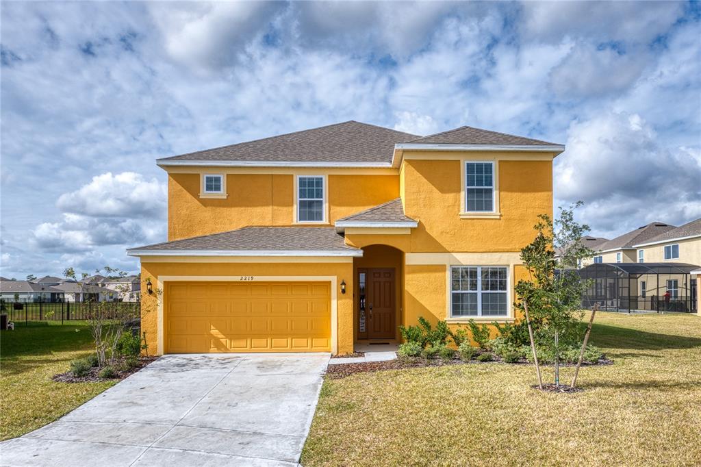 A two-story yellow stucco house features a two-car garage and a concrete driveway — 2219 CROFTON SPRINGS COURT, DAVENPORT, FL