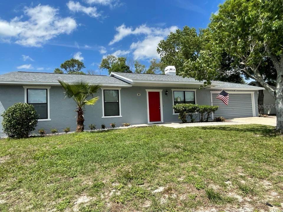A single-story gray house with a red front door and an attached garage — 512 GALLOWAY AVENUE, DELTONA, FL