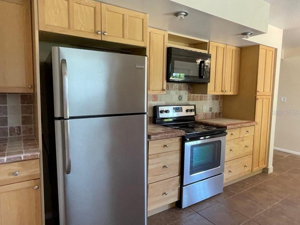 A kitchen features light wood cabinets, stainless steel appliances, and tiled countertops — 512 GALLOWAY AVENUE, DELTONA, FL